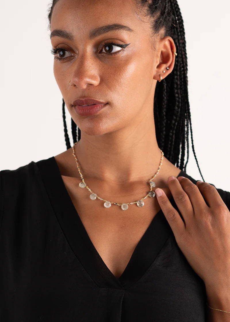 A model wearing a gold chain necklace with 7 tear drop natural coloured crystal charms