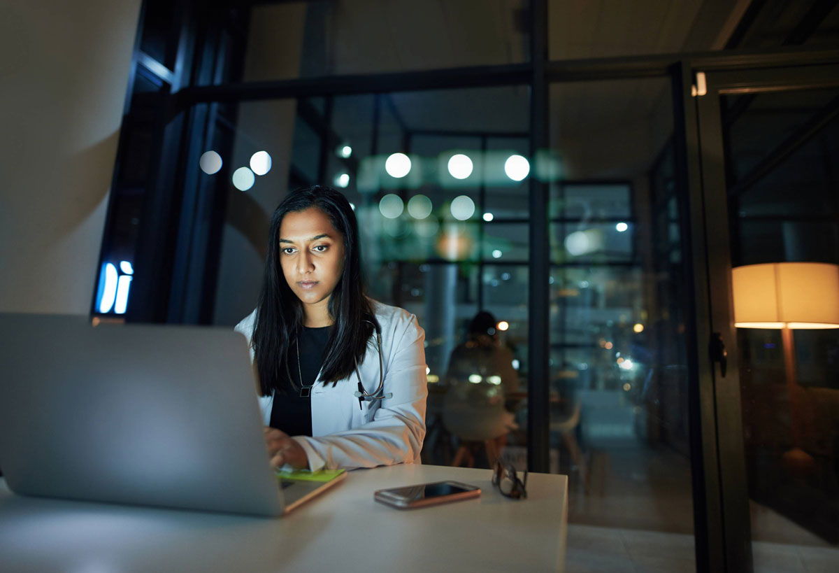 Woman doctor working on a laptop at night.