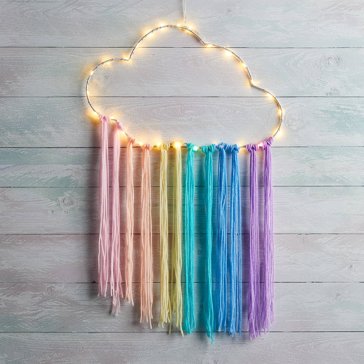 Rainbow dream catcher illuminated against wall