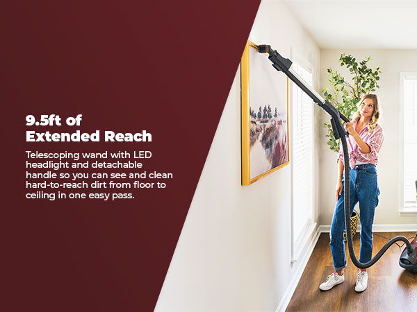 Woman using a vacuum with an extended reach to clean a wall.