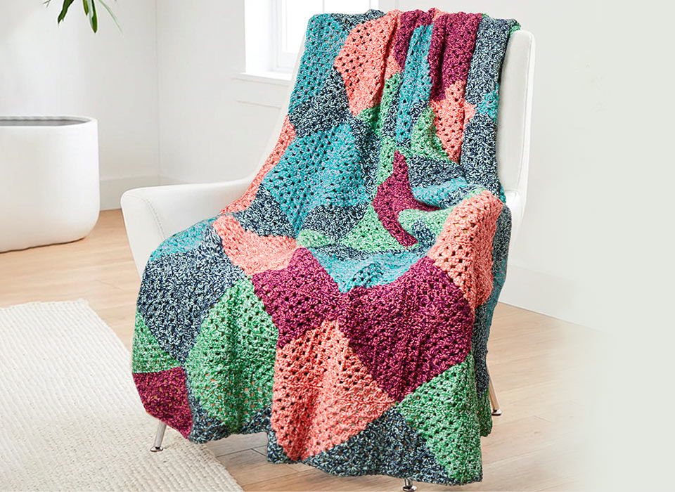 A colorful patchwork blanket draped over a chair in a bright room.