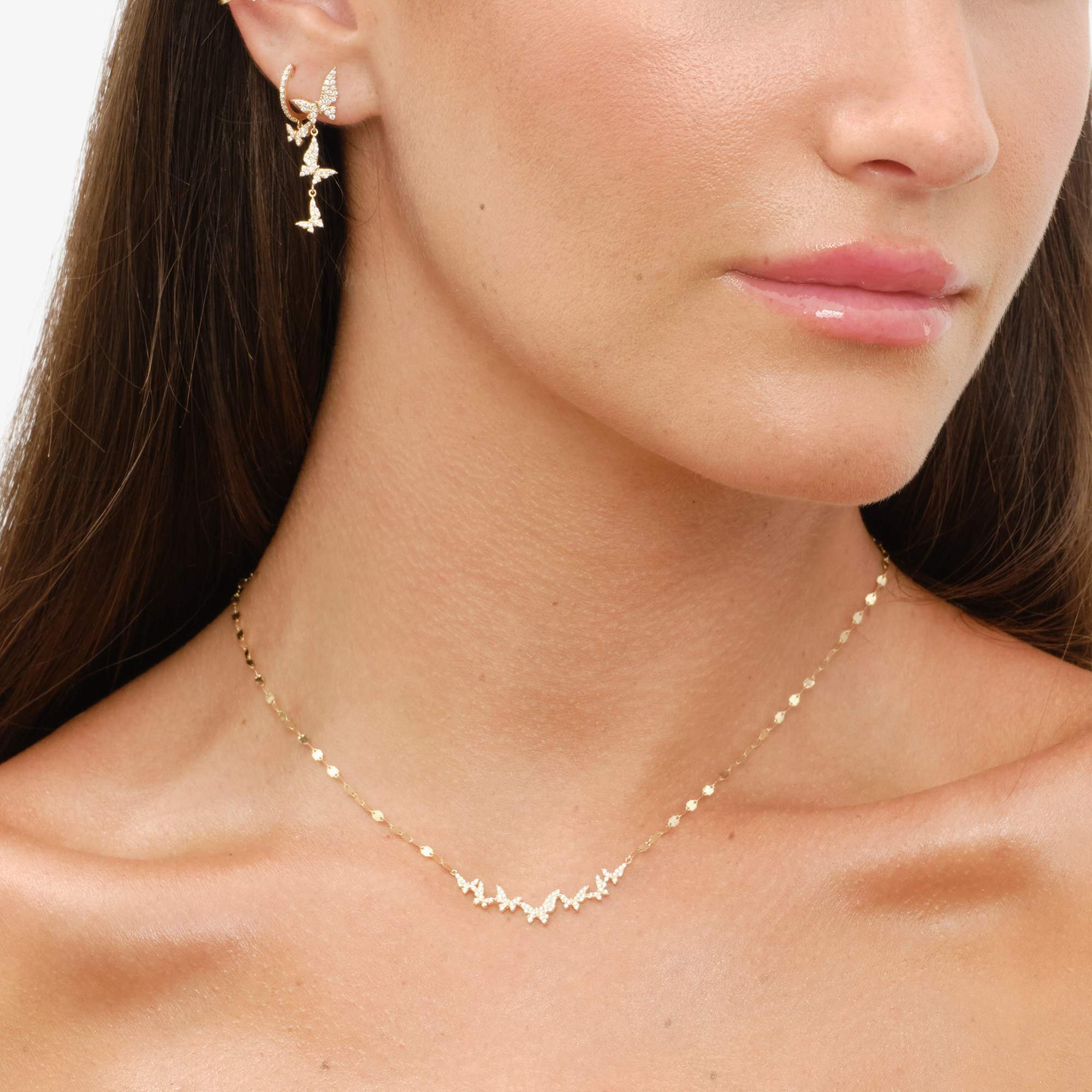 Woman wearing gold earrings and a delicate necklace, with a natural makeup look.
