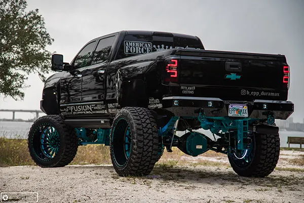 Rear three-quarter view of Brandon's black 2018 Chevy Silverado 2500 showing teal suspension, custom wheels, and lifted stance, install photo 2