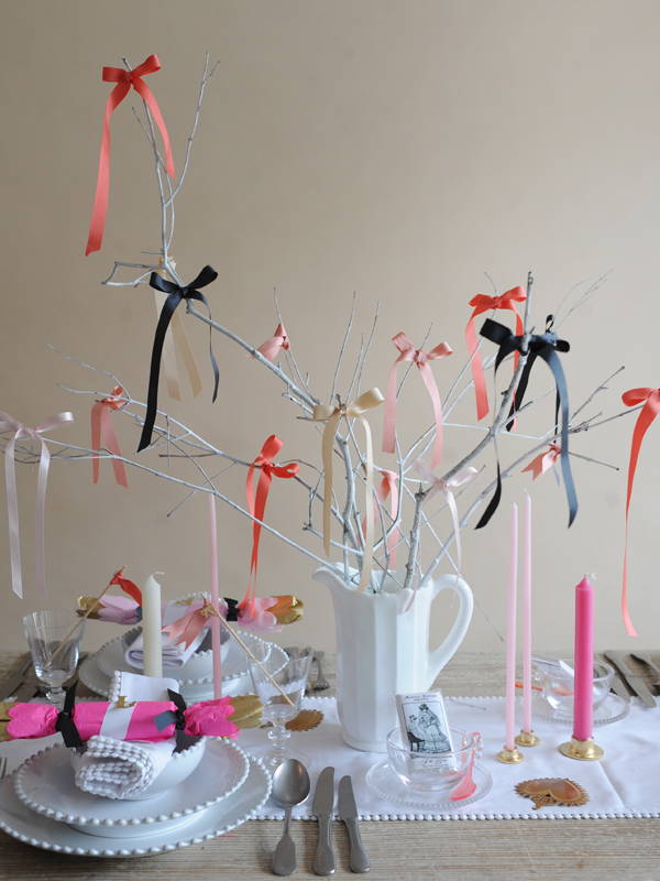 A Mosser white panel pitcher on the Hen Do table filled with white twigs covered in ribbon bows.