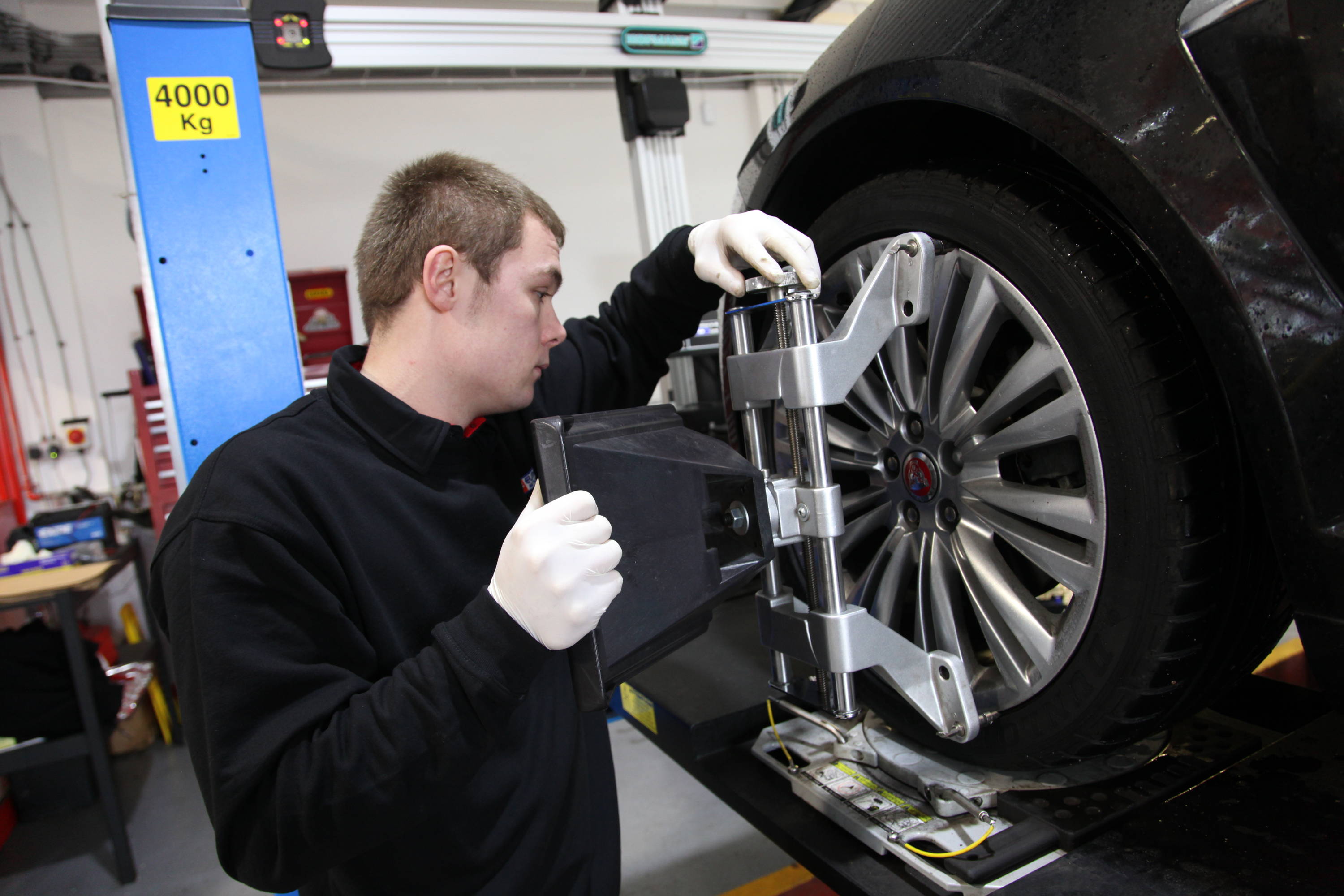 Car technician with machinery to attach trye to vehicle wheel 