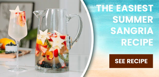 Summer sangria recipe with pitcher and glass of colorful fruit.