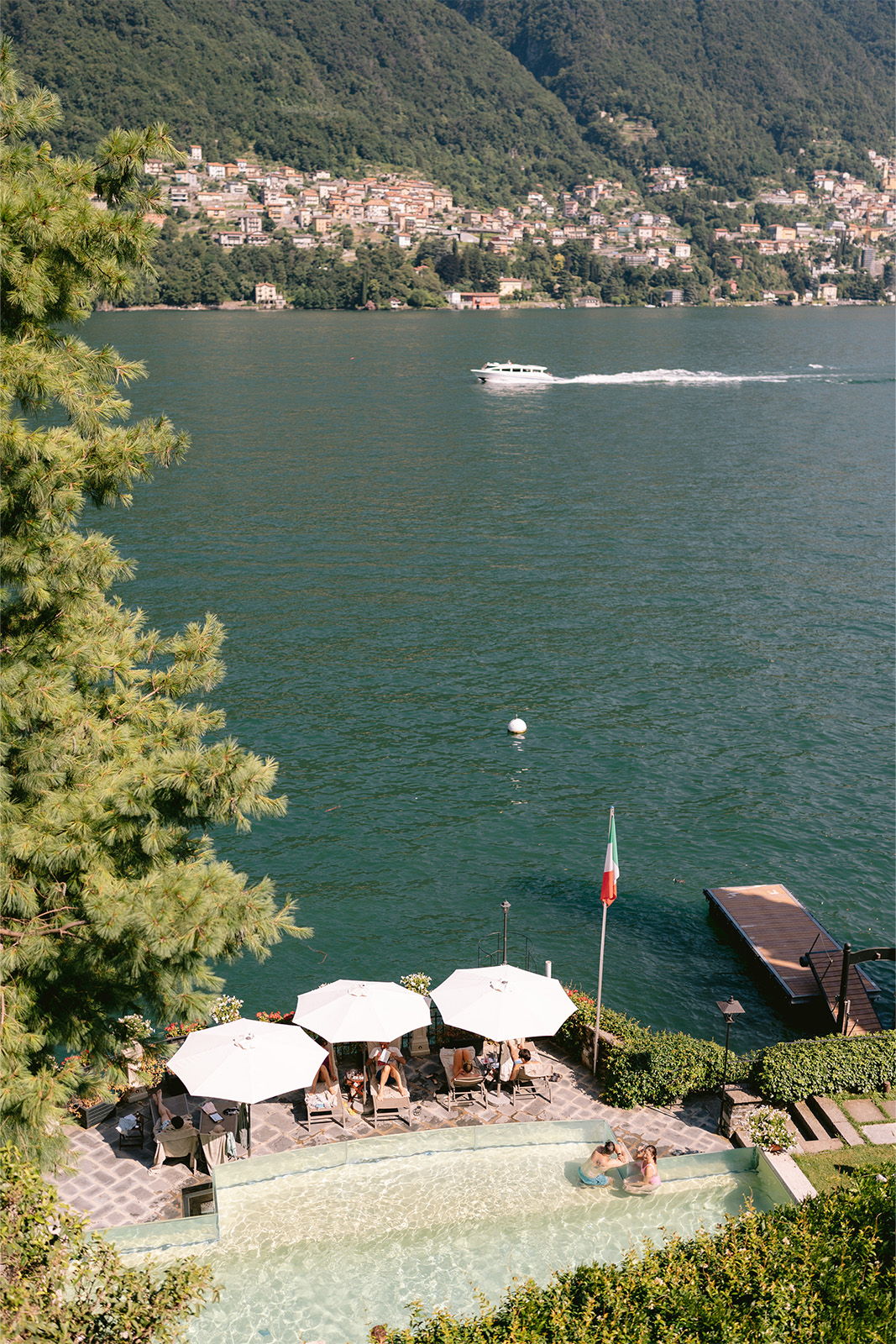 Scenic view of a lake with chairs, umbrellas, and a boat.