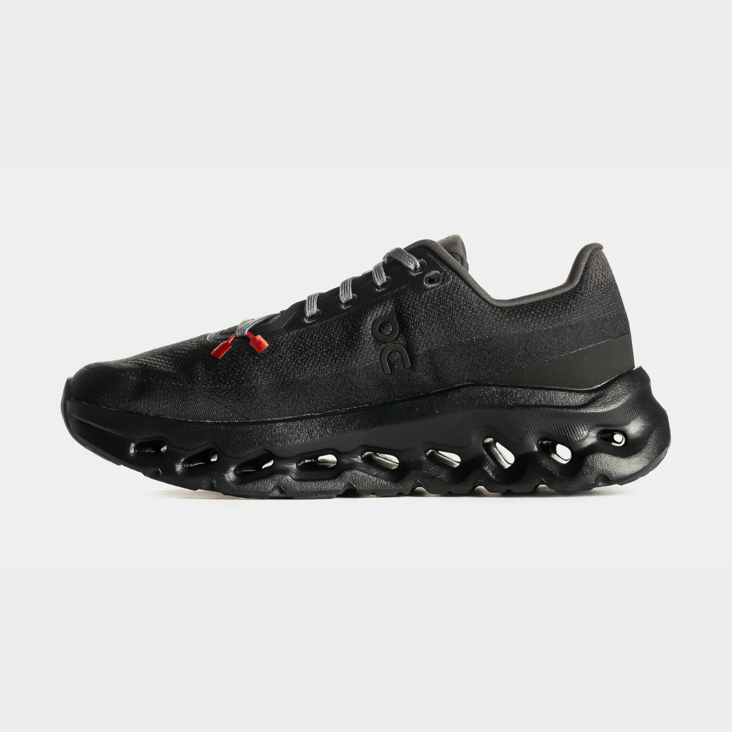 Black athletic shoe with a unique sole design and red accents.