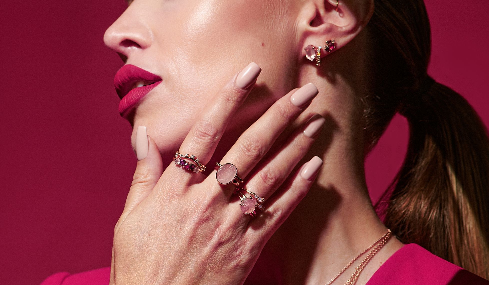 Profile of a woman with jewelry against a pink background.