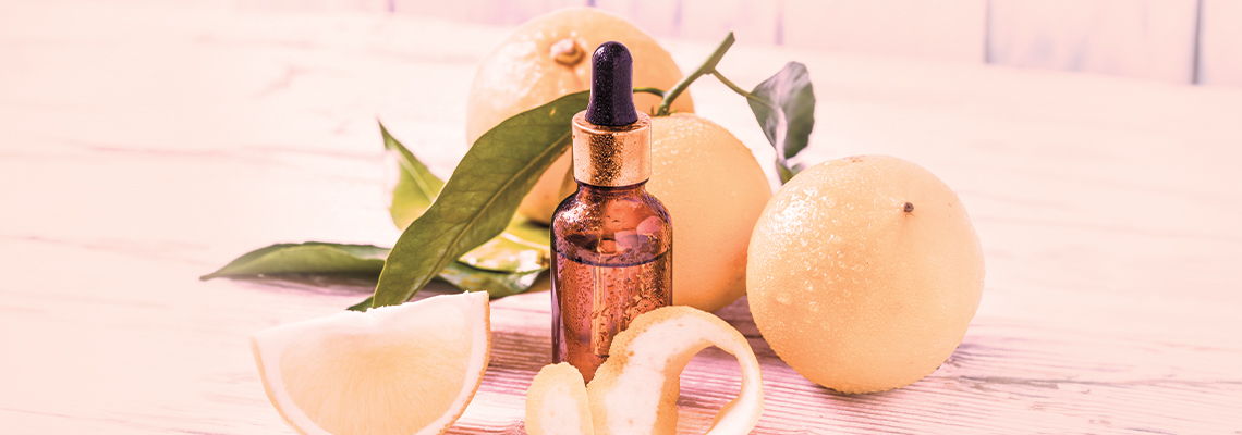 Bottle of oil surrounded by fruits and leaves on a light background.