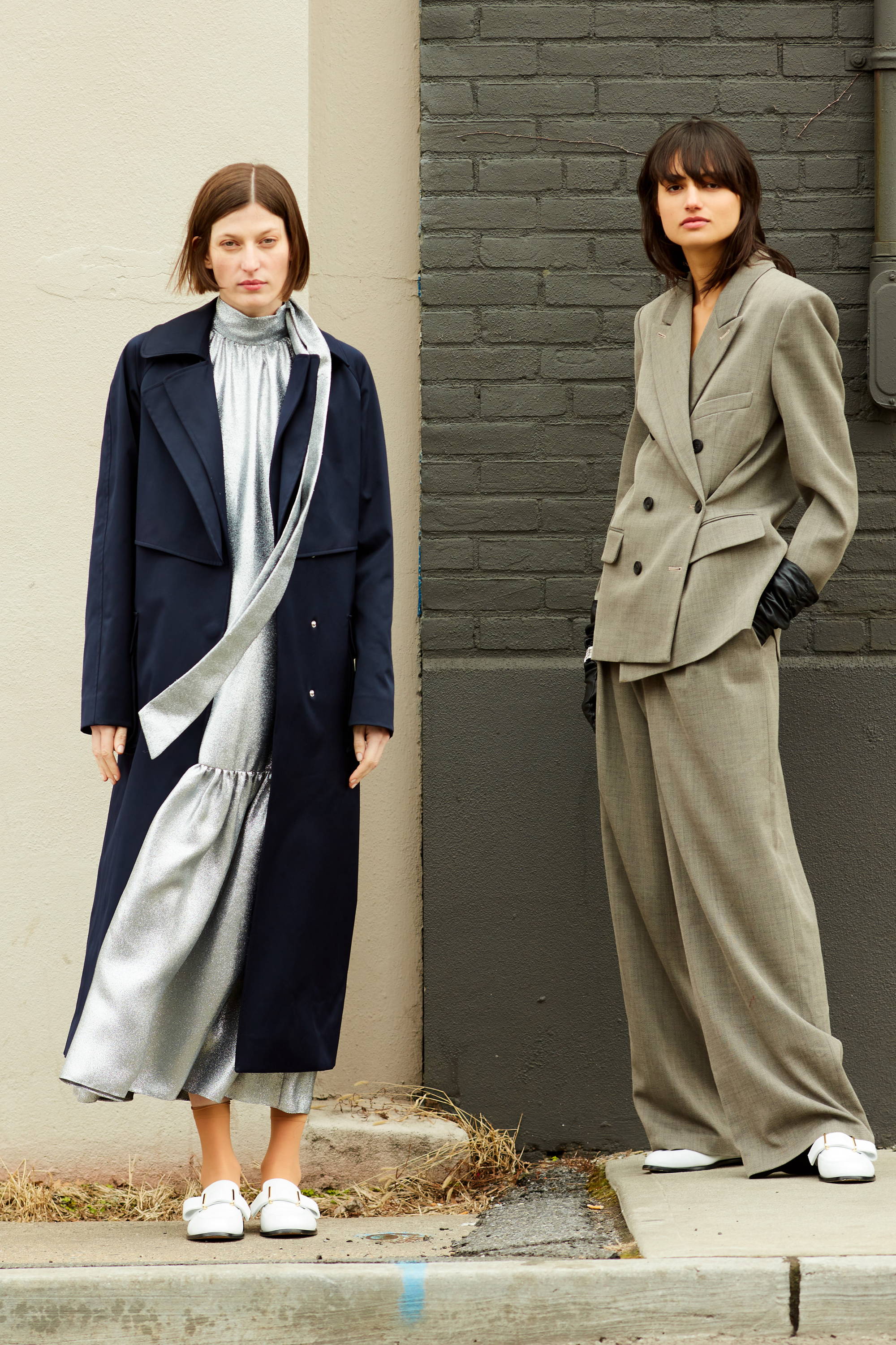 Two models in stylish outfits posing against a neutral background.