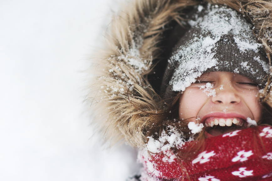 child coveres with snow laughing