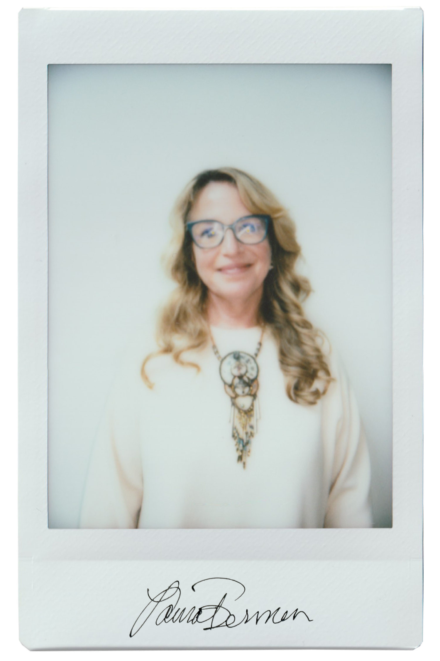 Woman with glasses and necklace, smiling in a polaroid-style photo.