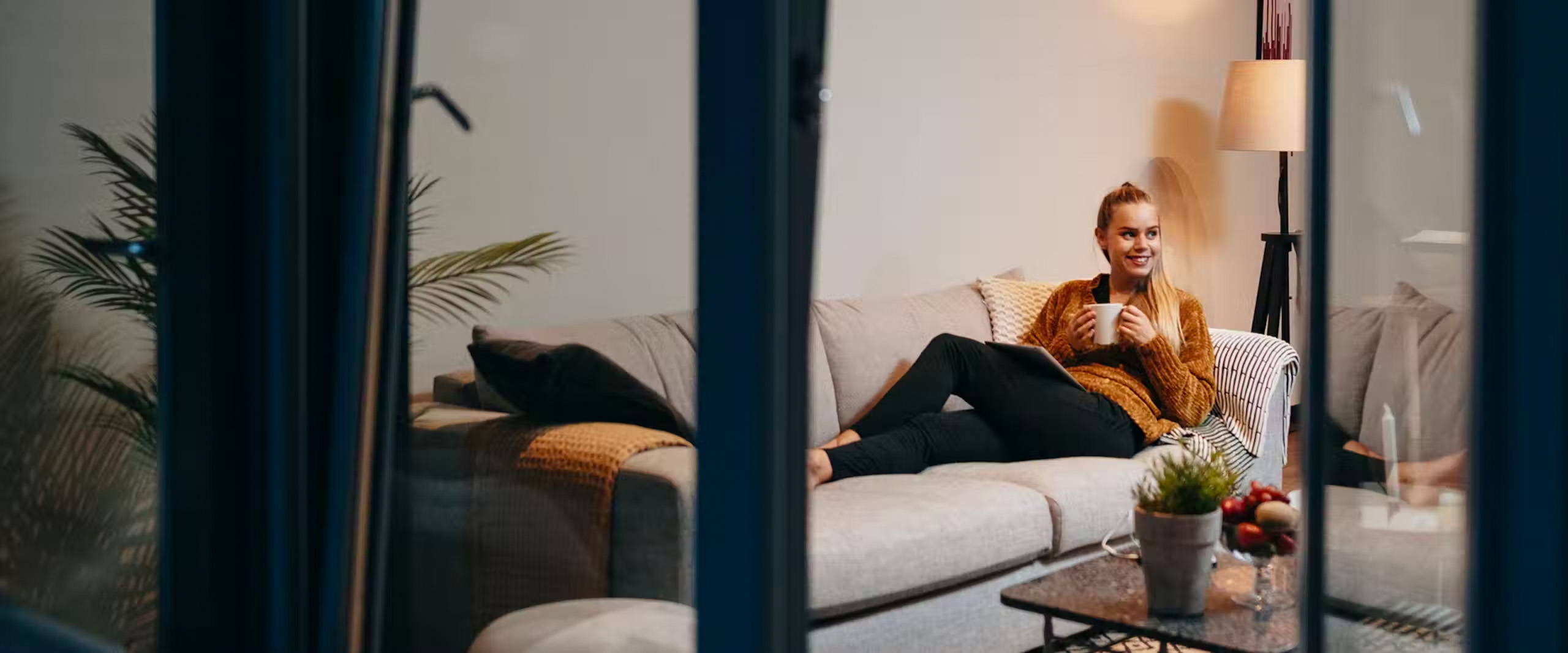 Woman reclining on a couch, with a cop of coffee