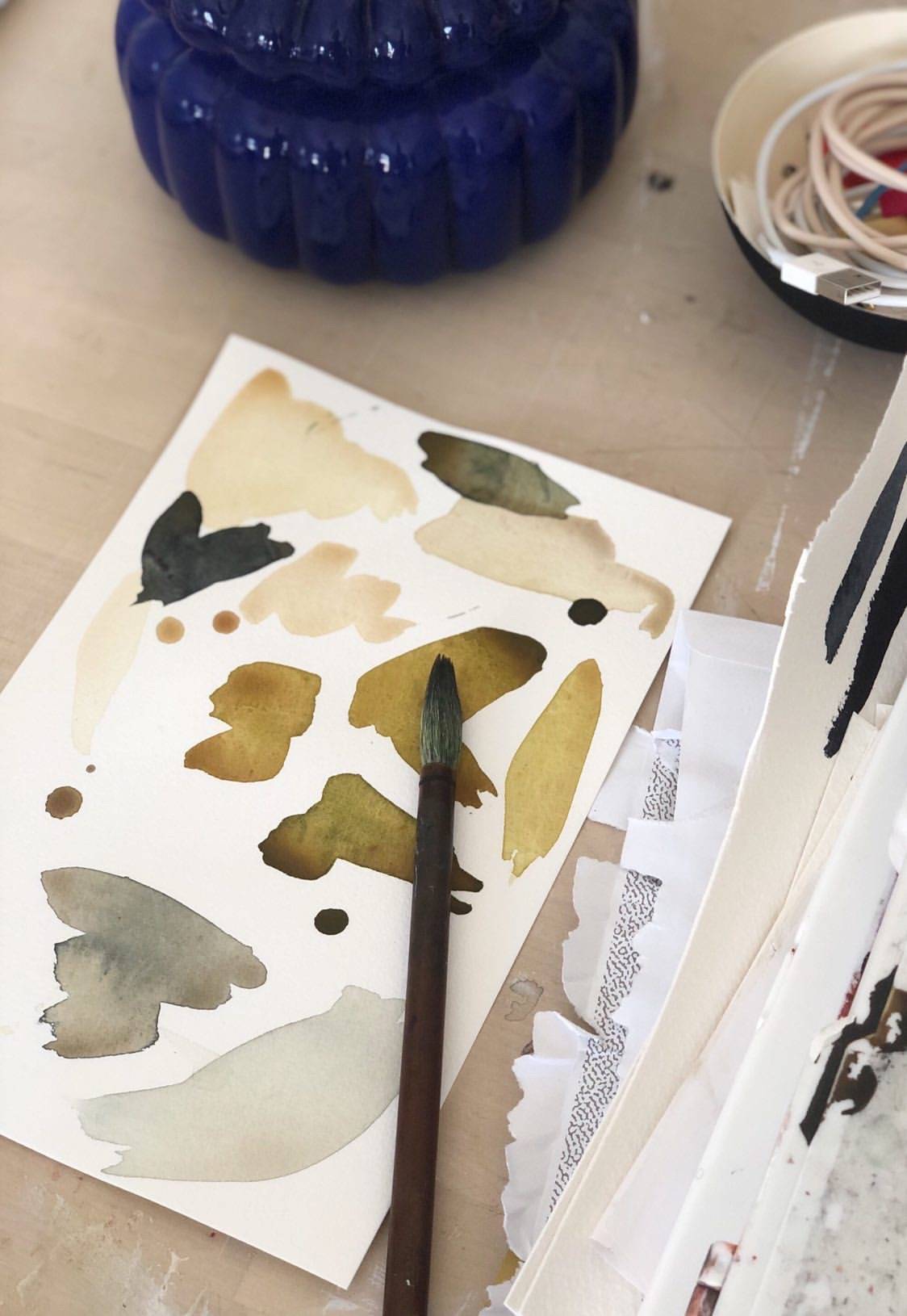 A sheet of paper shows experimental watercolor strokes. 