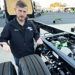 Person explaining vehicle components next to S2RV tires and chassis.