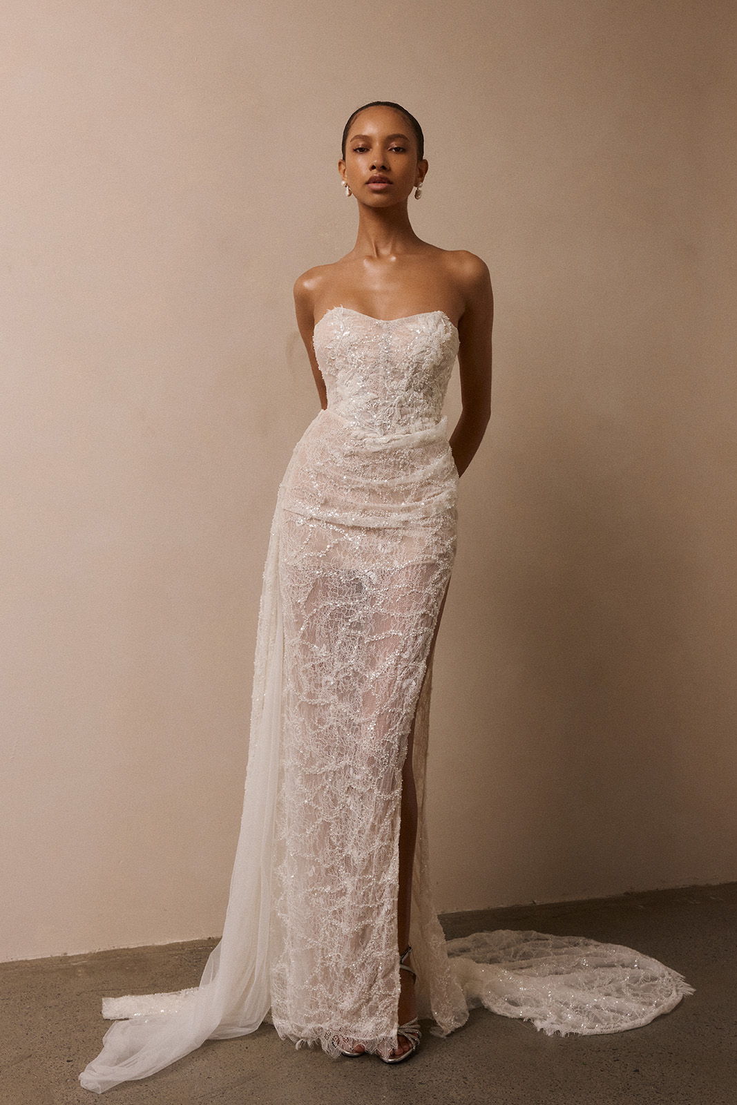 Model wearing a strapless lace wedding dress against a neutral background.