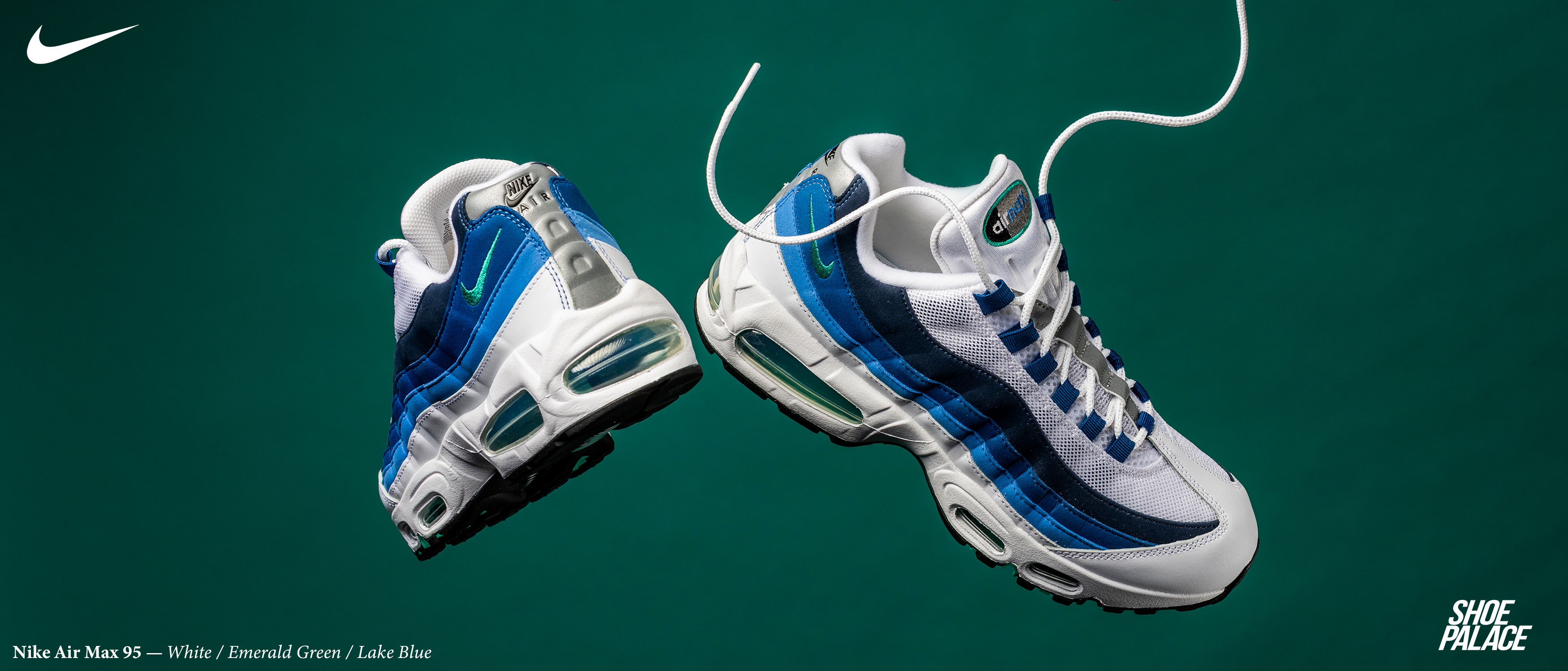 Nike sneakers in white and blue on a green background.