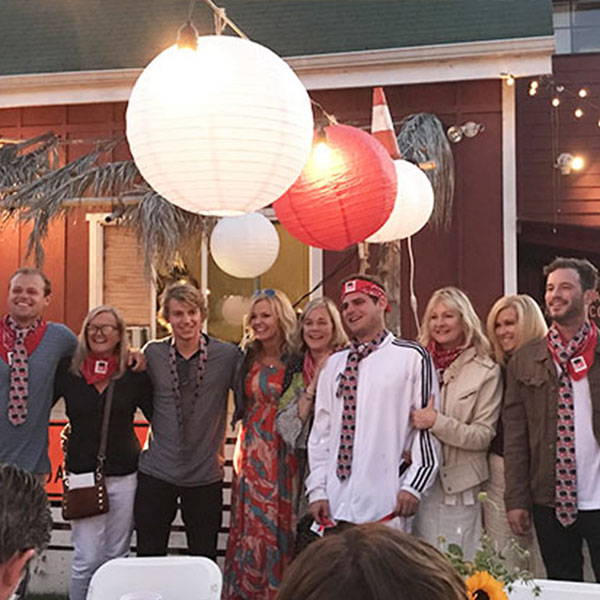 A group of male college graduates wearing custom ties while posing with their moms