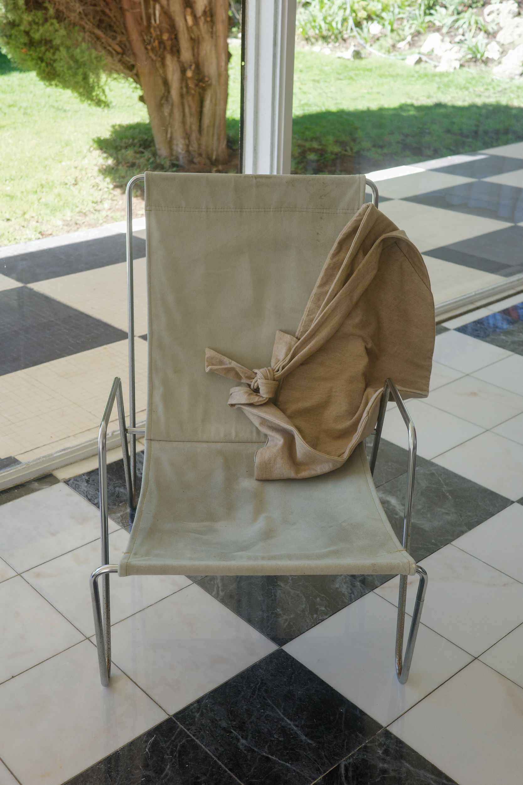 A chair with a beige cover draped over it, in a tiled room.