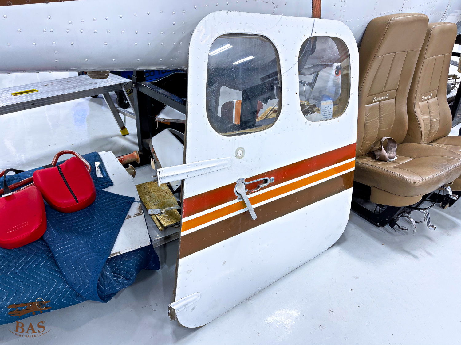 White aircraft door with orange stripes, resting on a storage surface.
