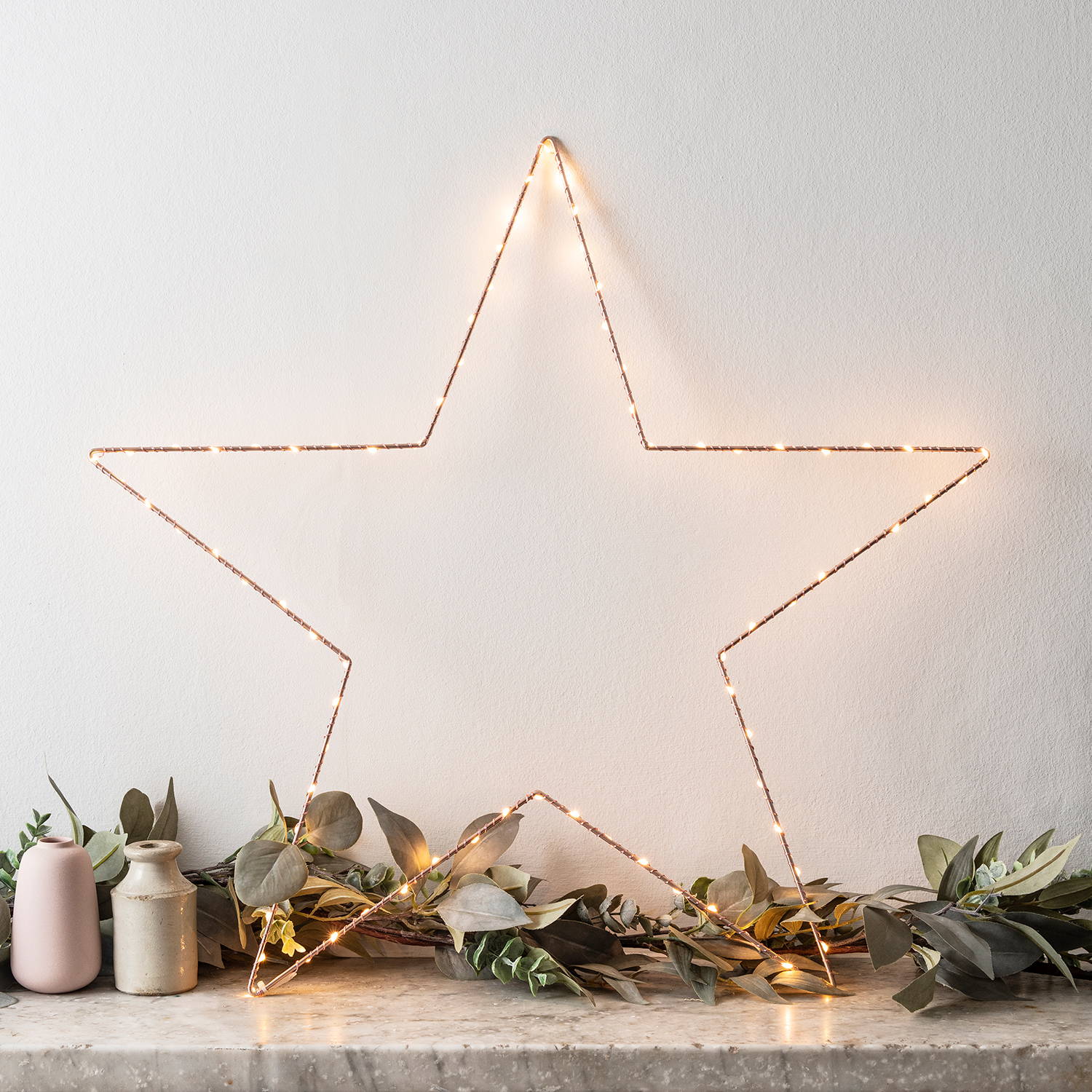 An illuminated star on a mantelpiece with foliage. 