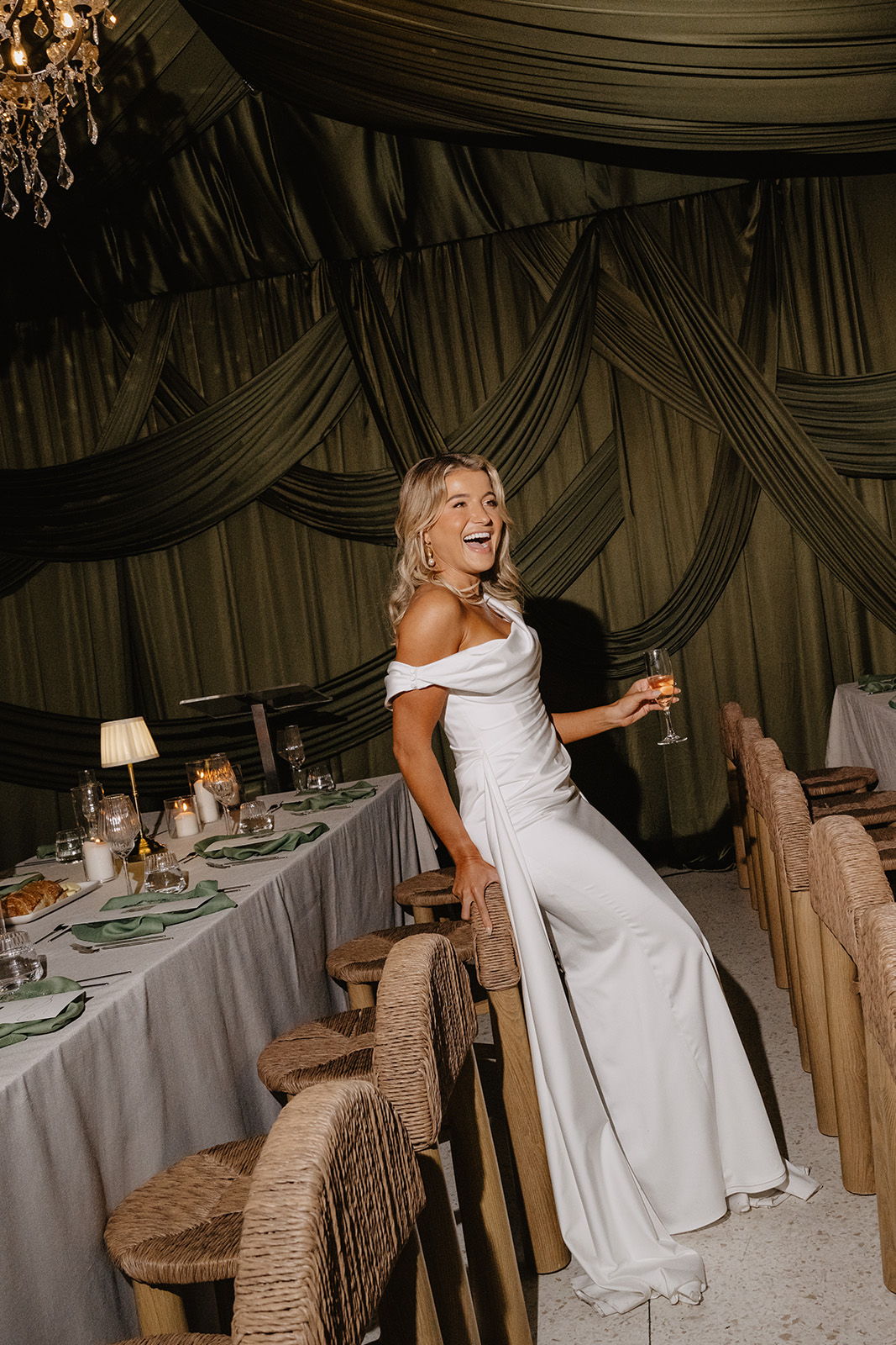 Woman in elegant white dress smiling at a festive table setting.