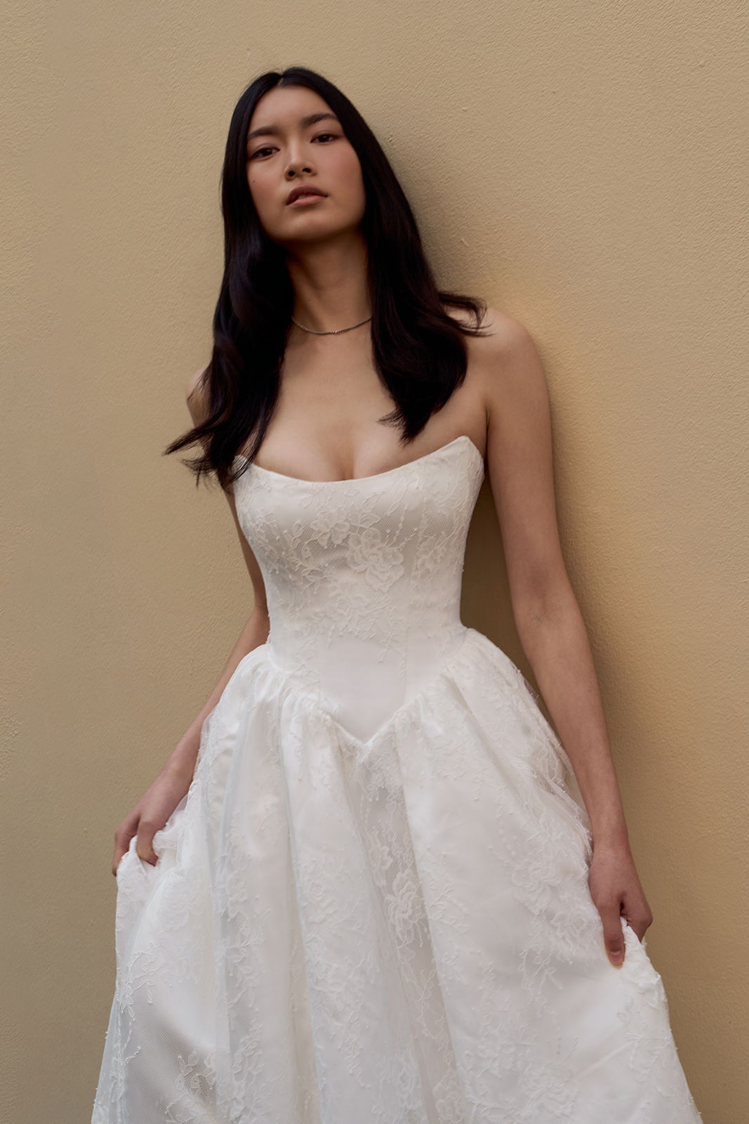 A woman in a strapless white dress against a neutral background.