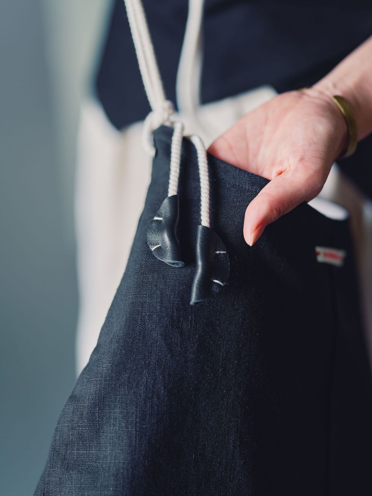 A hand holding a drawstring pouch with a toggle closure.