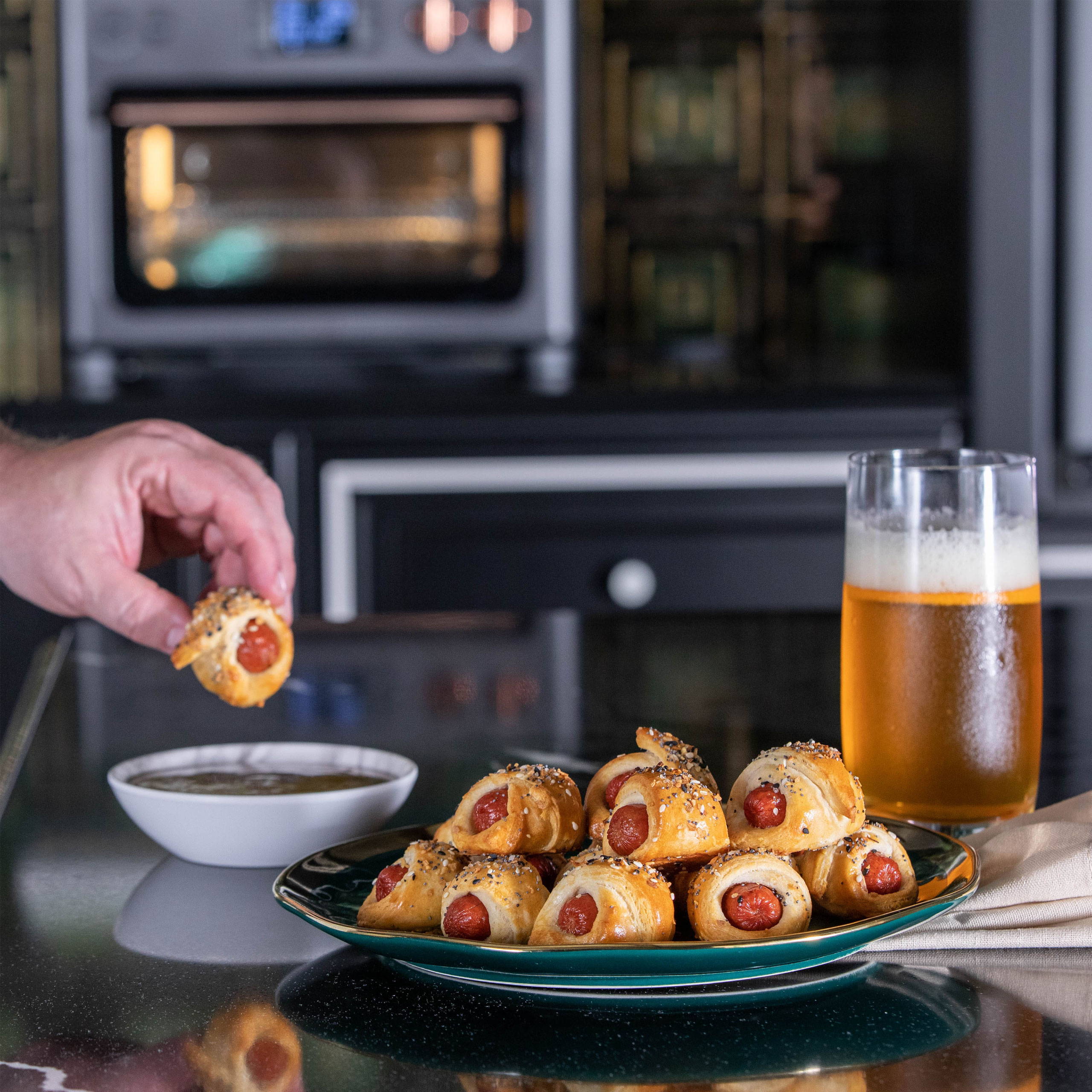 Hand dipping a pig in a blanket into sauce