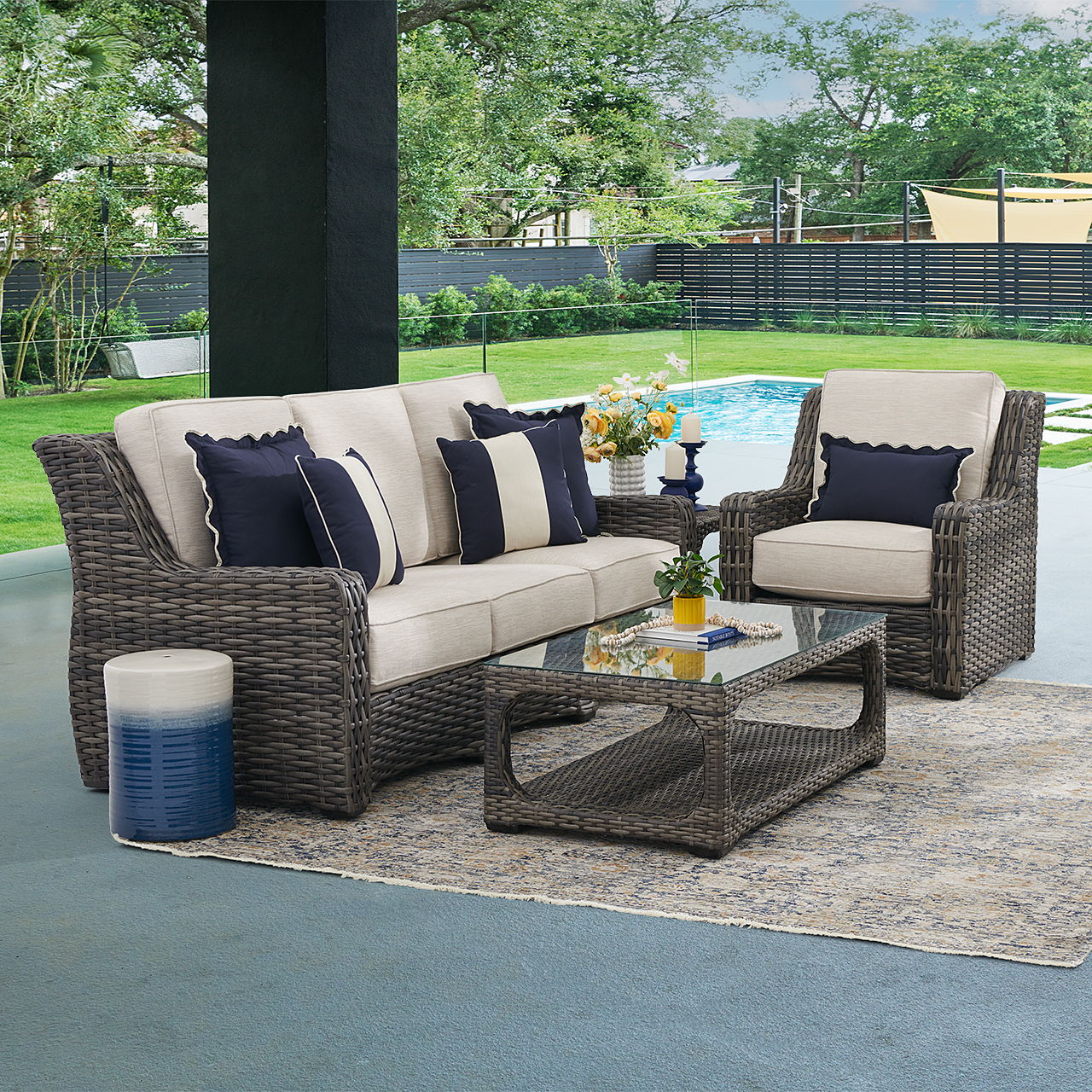 Outdoor seating arrangement with cushions, coffee table, and a pool view.