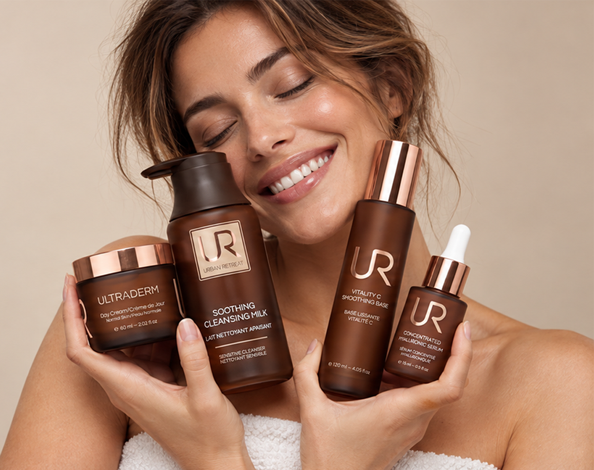 Smiling woman holding URBAN RETREAT skincare products against a neutral background.