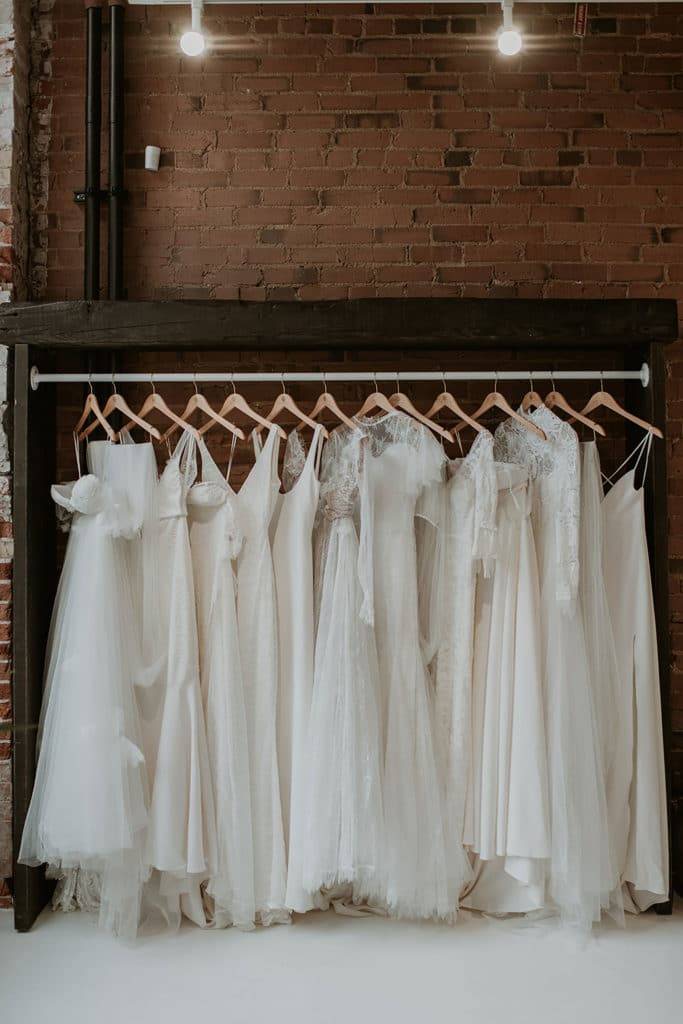 Lace wedding dresses hanging on a brick wall