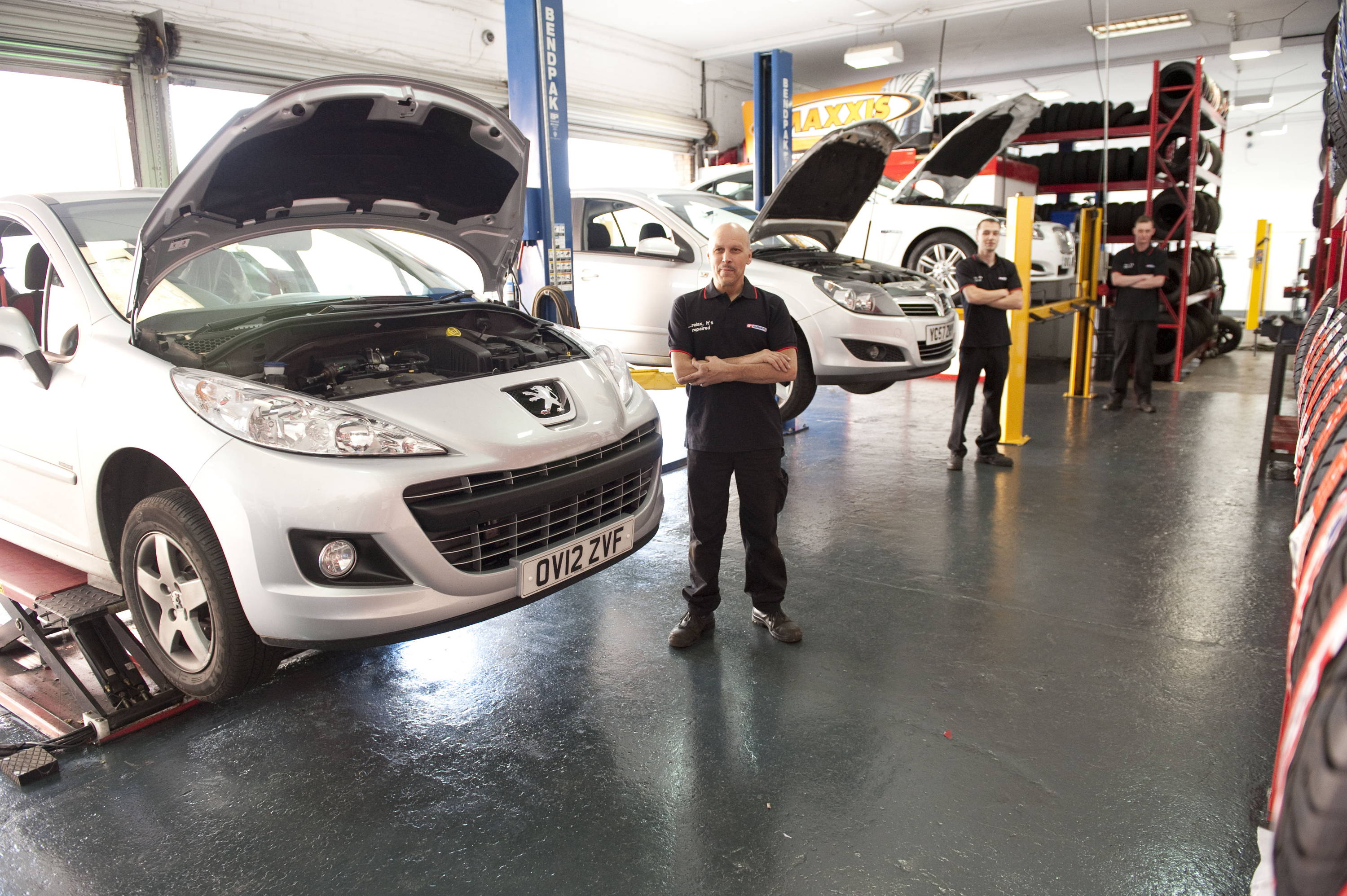 Car bonnet open of cars in garage, with mechanics stood next to them at Bloxwich Eurofit car garage