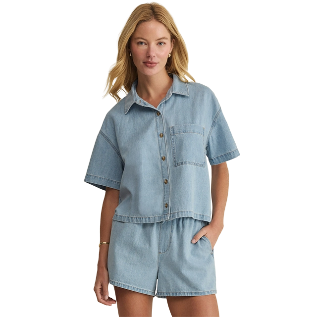 Woman wearing a denim short-sleeve shirt and matching shorts.