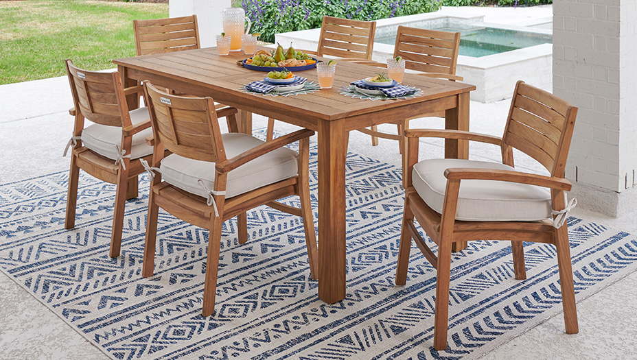 Outdoor dining table with chairs on a patterned rug.
