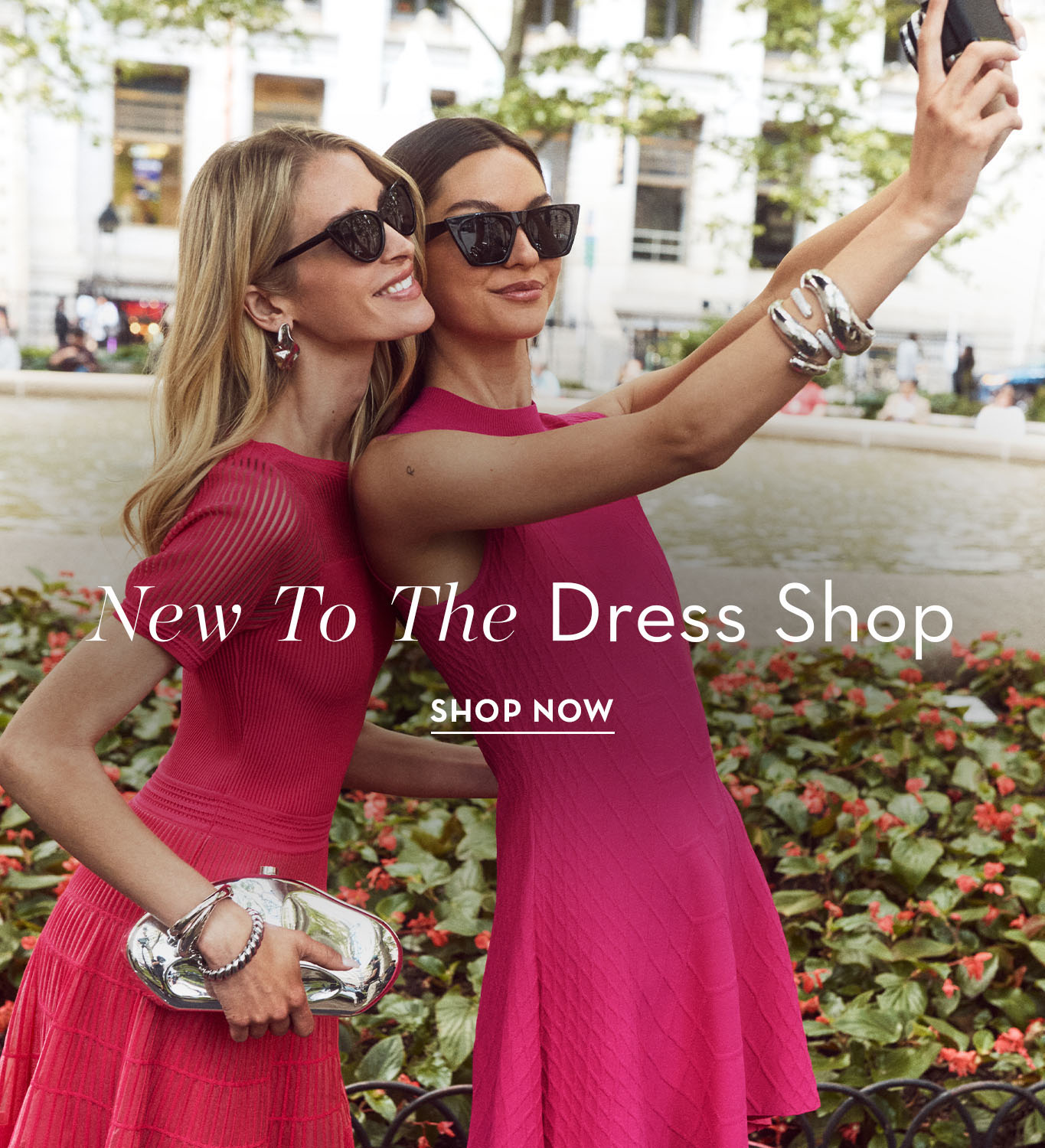 Two women in pink dresses taking a selfie outdoors.