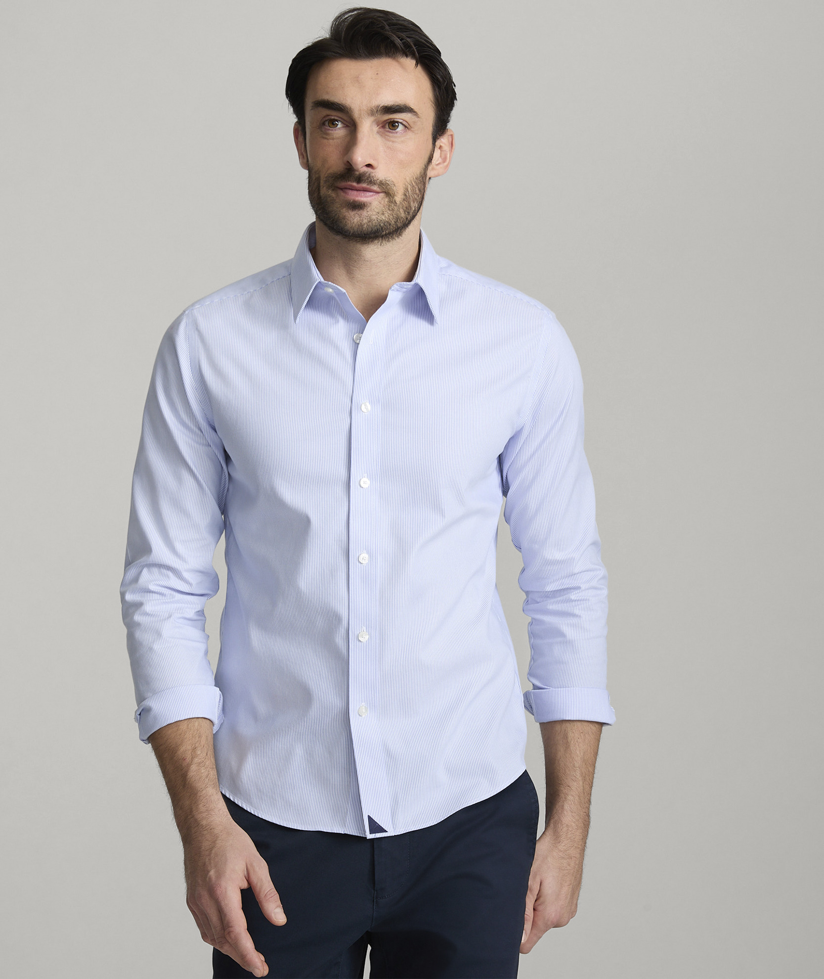 Man wearing a light blue button-up shirt against a gray background.