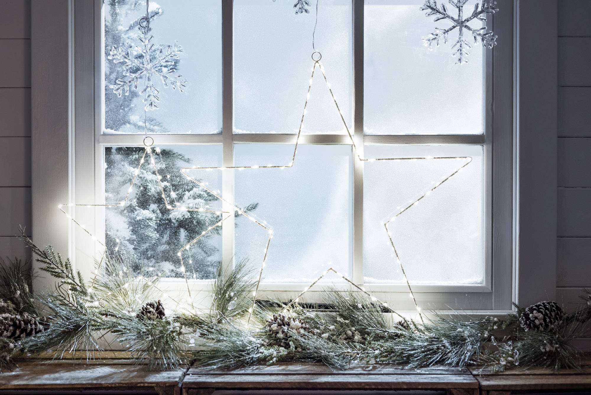 Weihnachtliches Fenster mit LED Sternen und Weihnachtsgirlande auf Fensterbank