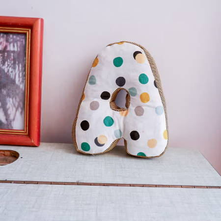 Stuffed fabric letter with dotted fabric on a desk