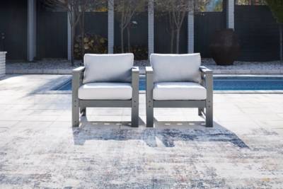 Two slate grey chairs sit in on a grey concrete floor with an in-ground pool behind them.