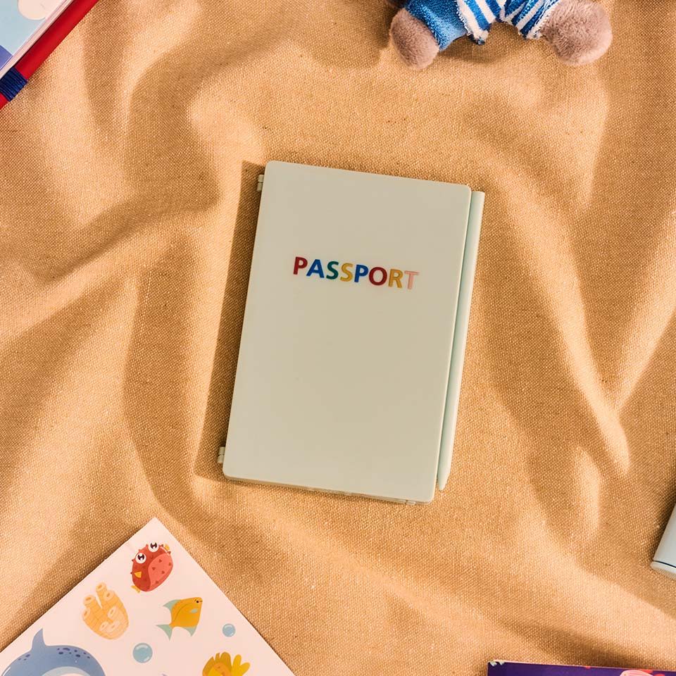 A passport on a beige surface surrounded by colorful items.