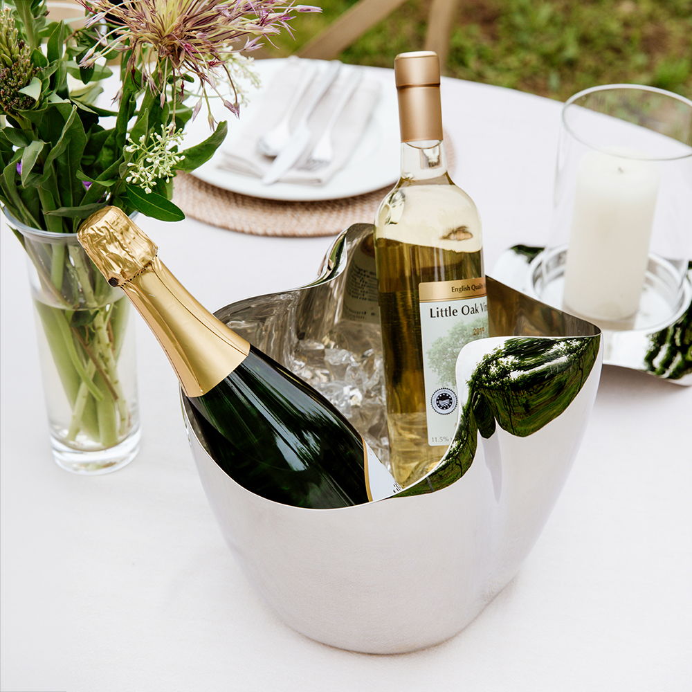 Champagne bottles in a Drift Champagne Bucket on a table with flowers.