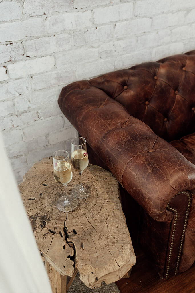 Deux verres à champagne sur une table en bois rustique avec un canapé en cuir chocolat.