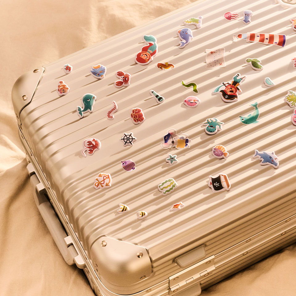 A decorated silver suitcase with colorful stickers on its surface.