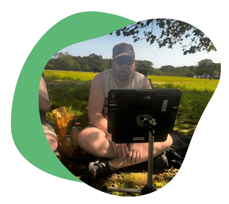 Person sitting outdoors, using a Grid Pad 13 in a grassy field.