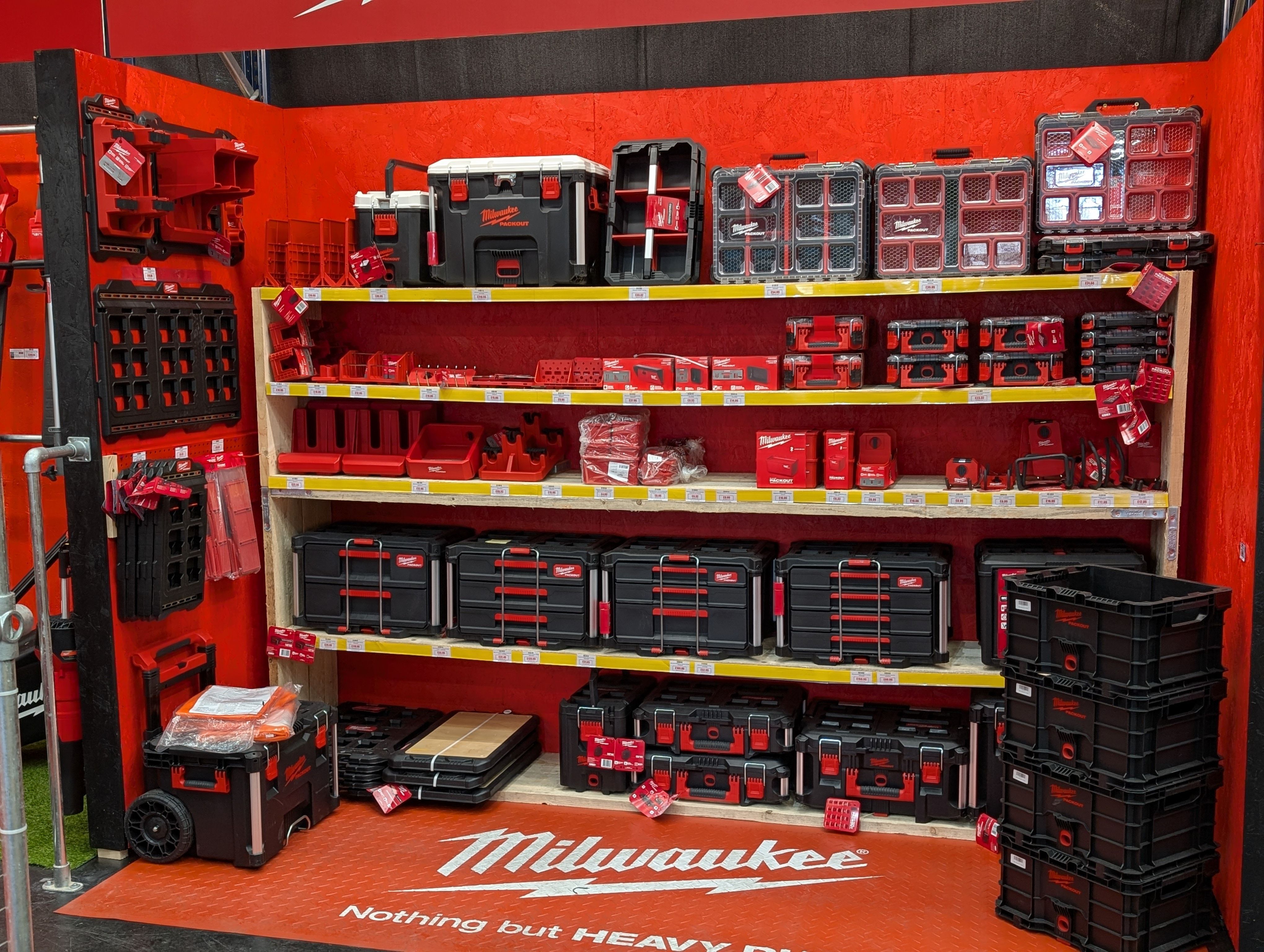 Display of Milwaukee tool storage products on shelves against a red background.