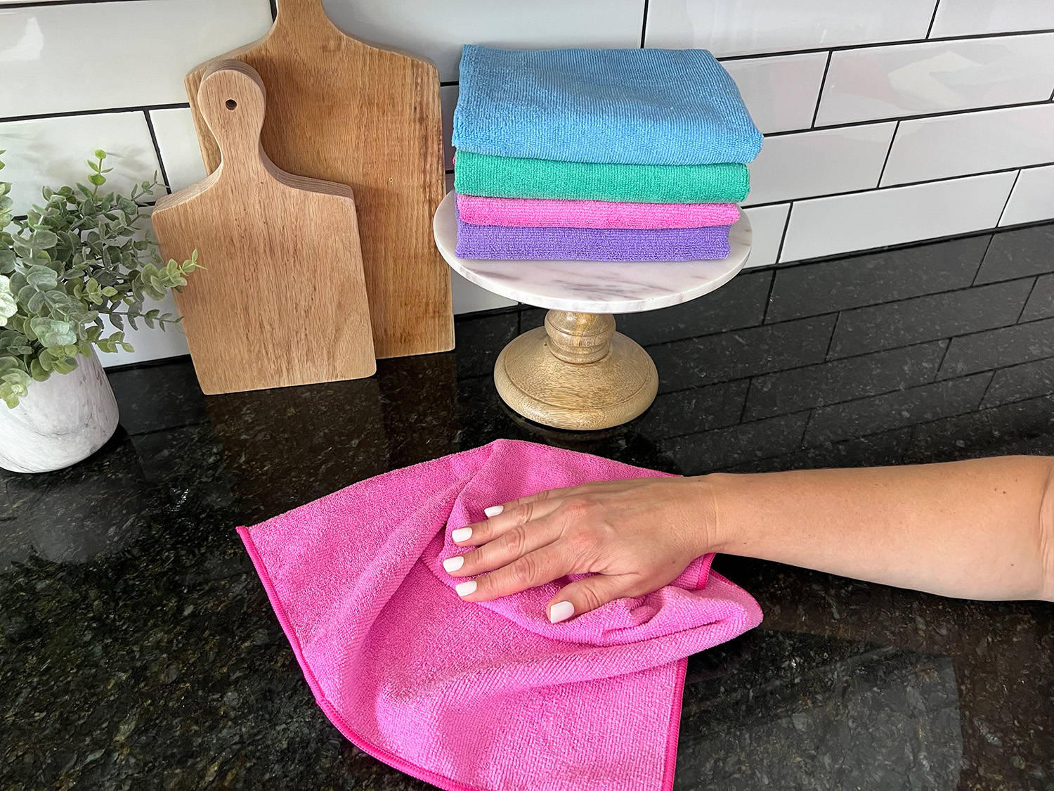 person wiping surface with pink microfiber towel