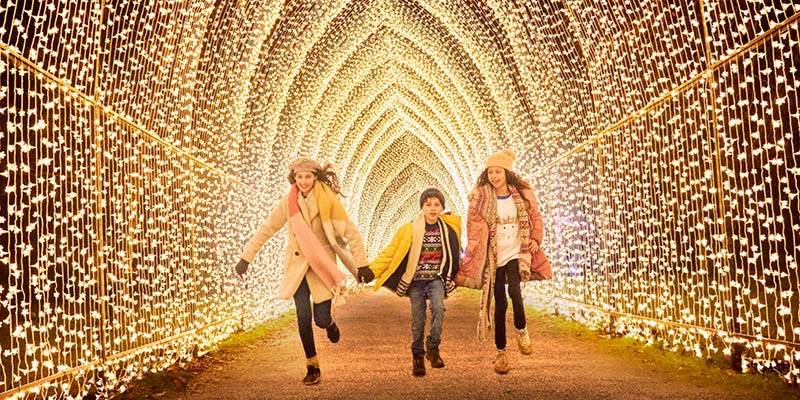 Children running through a light tunnel at Temple Newsam in Winter Clothes.