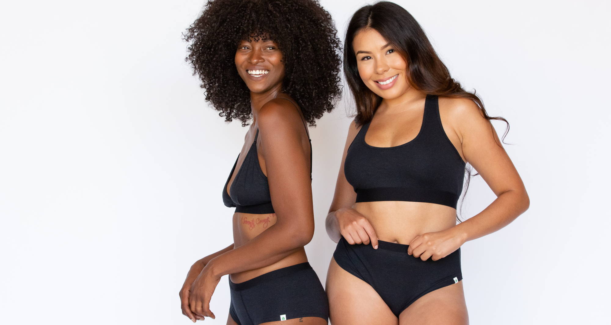 Two diverse women with dark hair model black underwear from WAMA, against a white background.